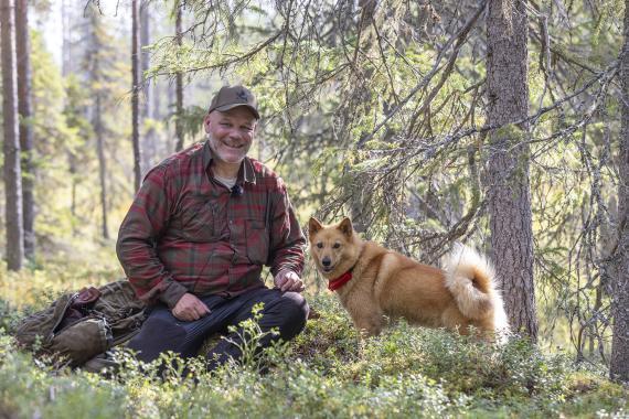 Blogin kirjoittaja Risto Ylitalo metsässä suomenpystykorvansa kanssa, istuu varvikossa hymyillen kameraan koira vierellään.